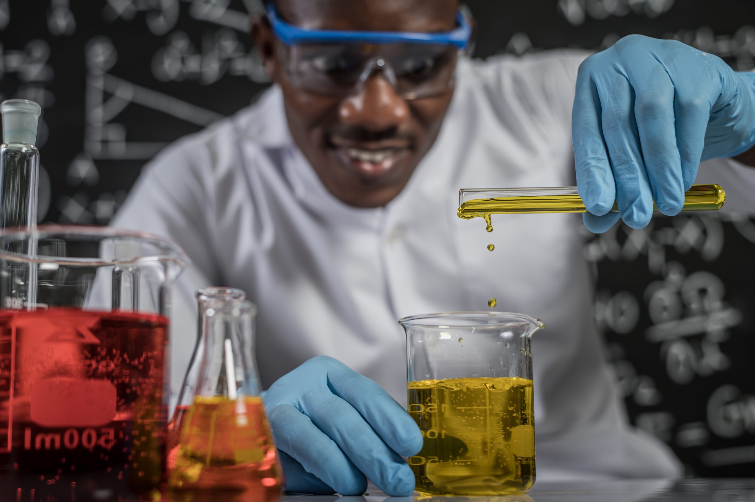 Scientists drop yellow chemicals into the glass at the laboratory.